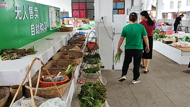 附近居民在自助菜攤買菜。永定區(qū)委組織部供圖