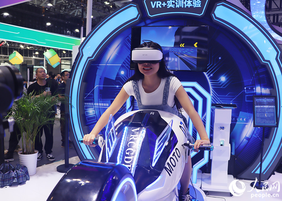 觀眾頭戴VR眼鏡，體驗(yàn)坐在摩托車(chē)上風(fēng)馳電掣的快感。人民網(wǎng) 黃東儀攝