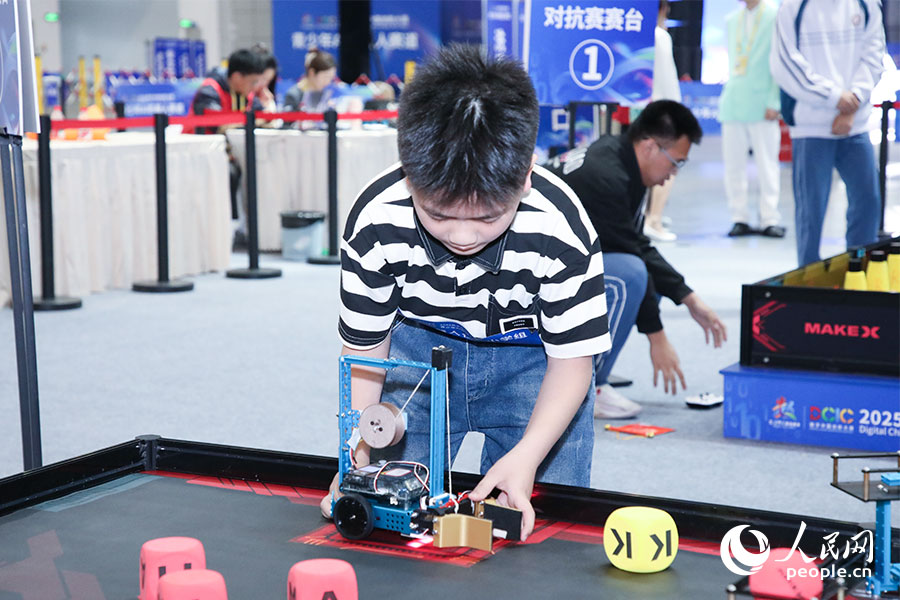 比賽間隙，選手調(diào)整機(jī)器人的位置。人民網(wǎng)記者 焦艷攝