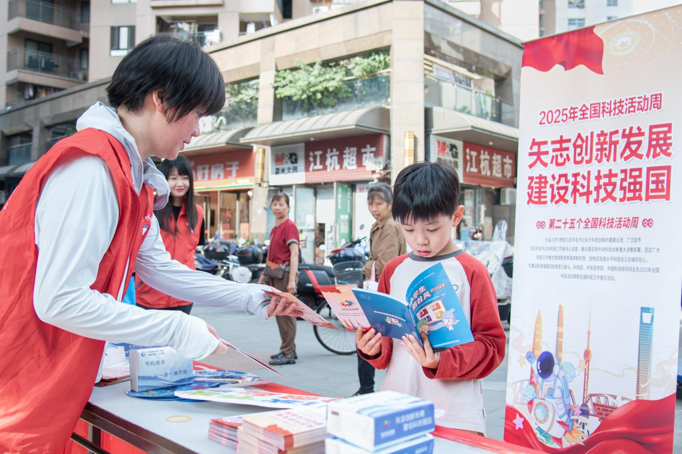 2025年全國科技活動(dòng)周現(xiàn)場，志愿者向小學(xué)生遞發(fā)水利科普資料。陳美蓉?cái)z