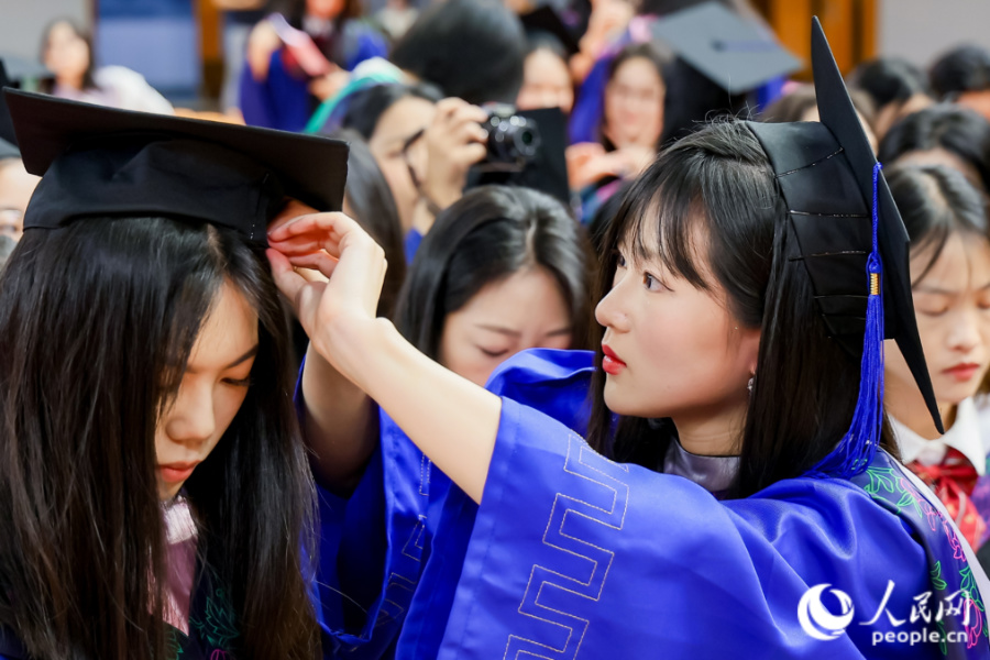 畢業(yè)生互相整理儀容。人民網(wǎng)記者 陳博攝