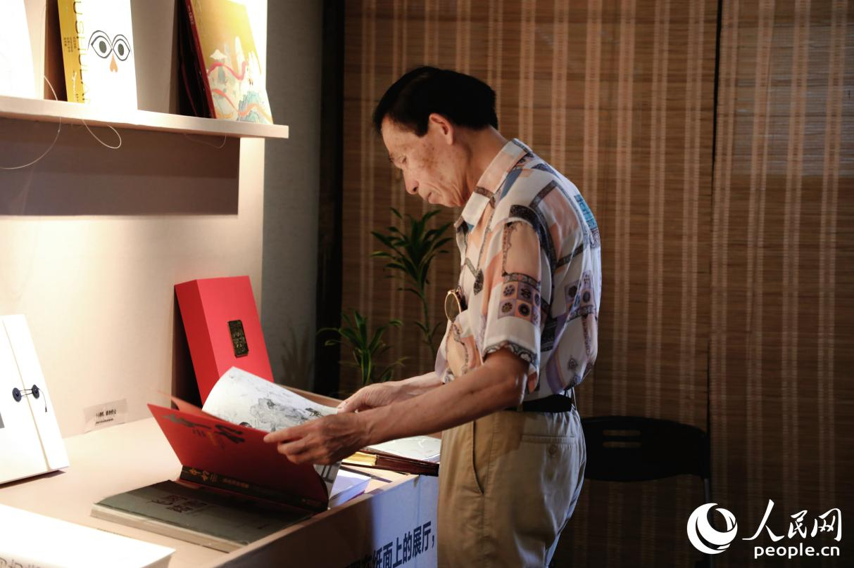一位老人翻閱展出書籍。人民網(wǎng) 李唯一攝