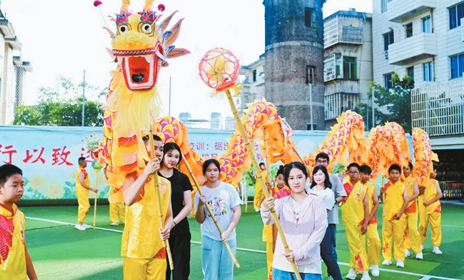 營(yíng)員們?cè)邶垘r學(xué)院附屬小學(xué)與學(xué)生一同舞龍。龍巖市融媒體中心供圖