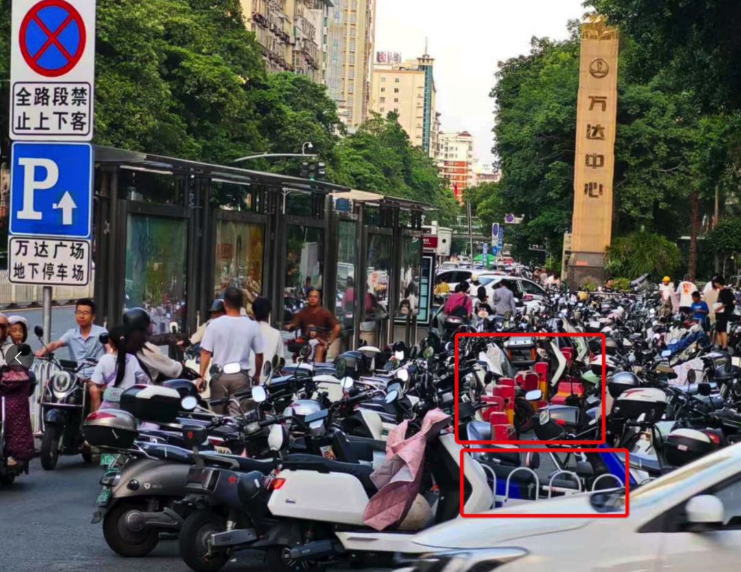 浦西公交站背后路段設(shè)置了非機動車停車區(qū)域，但仍有大量電動車直接停放在白色護欄和紅色隔離墩（紅框位置）外的非機動車道上。李先生攝于7月2日