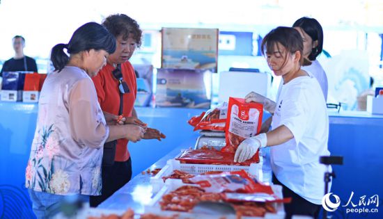 游客在澳角村采購當(dāng)?shù)睾ur加工產(chǎn)品。人民網(wǎng) 李昌乾攝